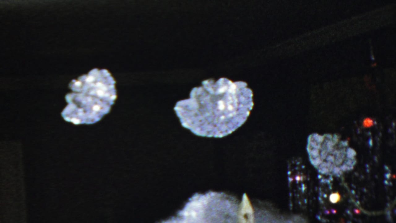 1949 Seaside, New Jersey 8mm frame showing suspended snowflake ornaments over a miniature chapel with artificial snow in a dark Christmas display.
