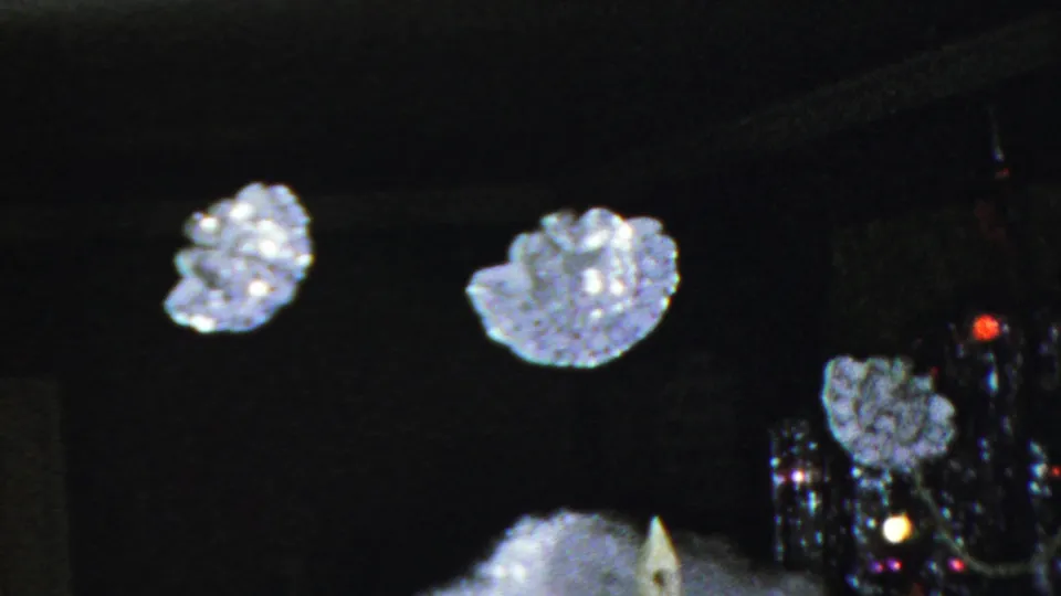 1949 Seaside, New Jersey 8mm frame showing suspended snowflake ornaments over a miniature chapel with artificial snow in a dark Christmas display.