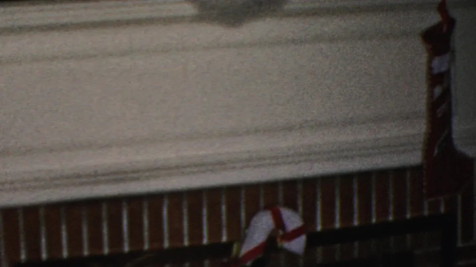 1949 Seaside, New Jersey home-movie frame showing a fireplace mantel edge, red-and-white stocking, and part of the Christmas display above.