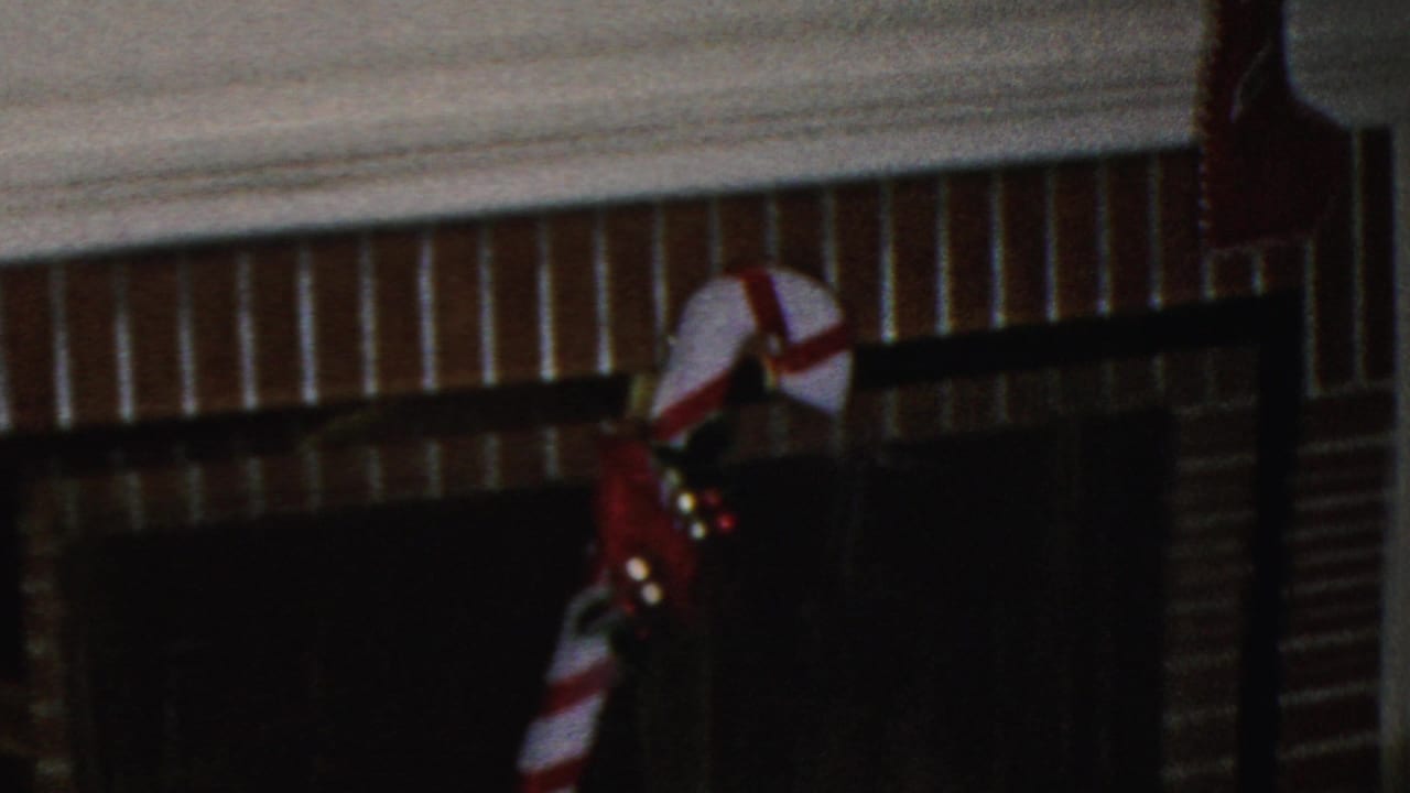 A 1949 Seaside, New Jersey home-movie frame shows a brick fireplace with a dark screen, red-and-white candy cane decoration, and small holiday lights.