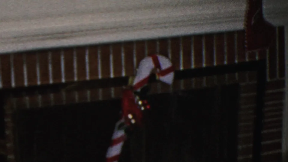 A 1949 Seaside, New Jersey home-movie frame shows a brick fireplace with a dark screen, red-and-white candy cane decoration, and small holiday lights.