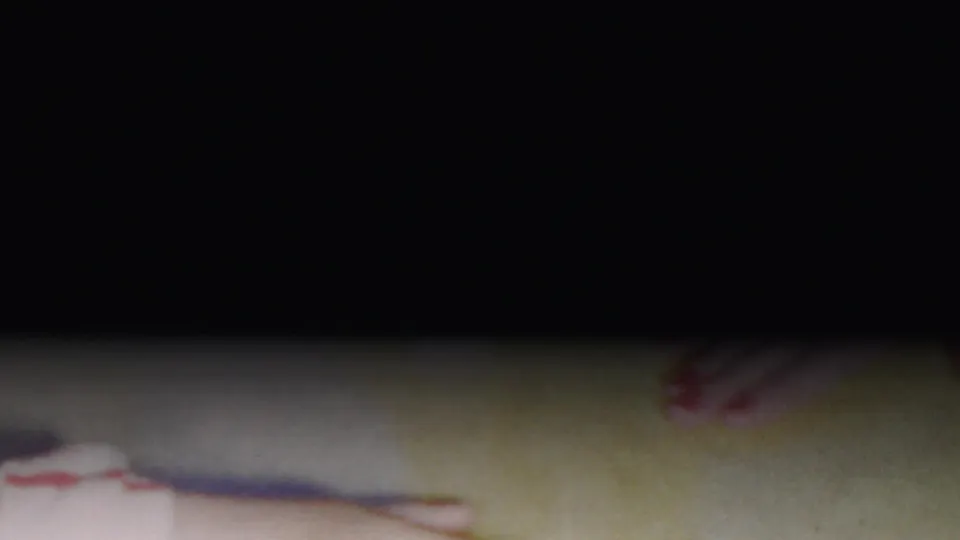 A mostly underexposed 8mm frame shows only partial red-and-white striped clothing and a small foot at the edge, suggesting the handheld camera has drifted away from the puppy.