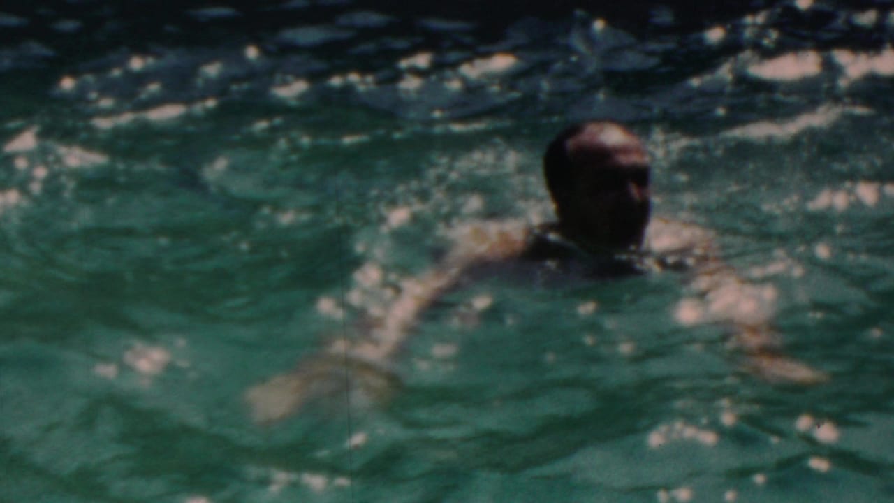 An adult man swims through the turquoise pool in the supplied 1949 Seaside, New Jersey footage, his head and arm visible amid small splashes.