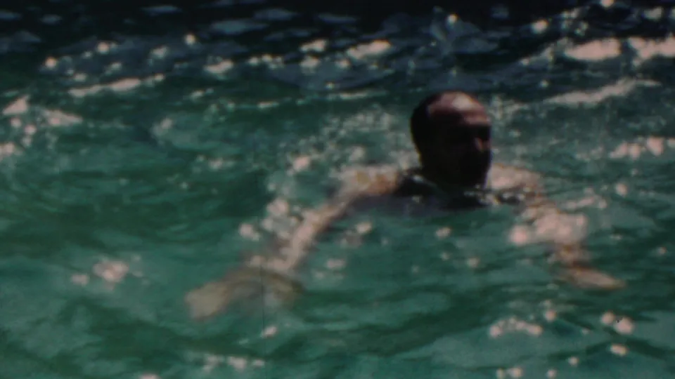 An adult man swims through the turquoise pool in the supplied 1949 Seaside, New Jersey footage, his head and arm visible amid small splashes.