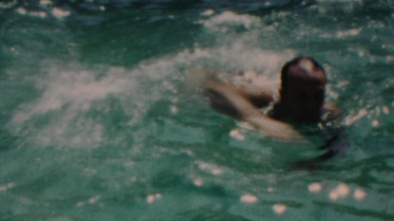 In metadata-supported Seaside, New Jersey, 1949, a swimmer moves across turquoise pool water in soft, grainy 8mm home-movie footage.