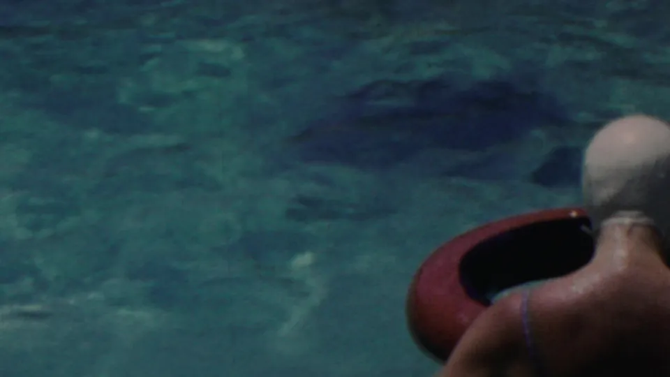 A woman wearing a white swim cap and dark swimsuit is seen from behind beside a red inner tube in the Seaside, New Jersey pool footage.