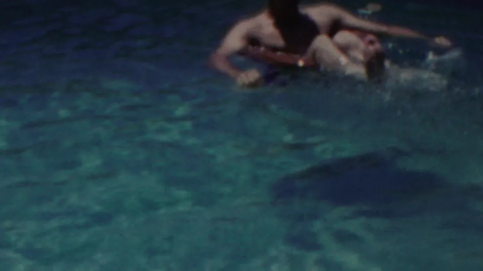 A swimmer floats near the top of the frame on a red inner tube while the blue-green pool water fills most of the 1949 Seaside, New Jersey home-movie view.