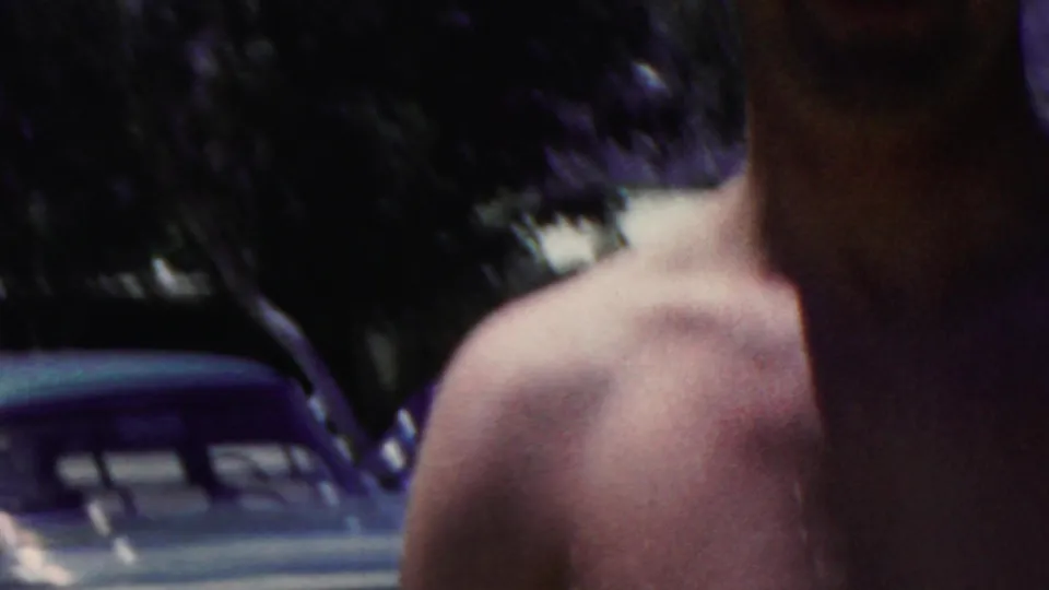 The frame shows a cropped shirtless figure near the pool, with blue pool water, a pool edge, and dark foliage or structures behind them in the supplied 1949 Seaside footage.