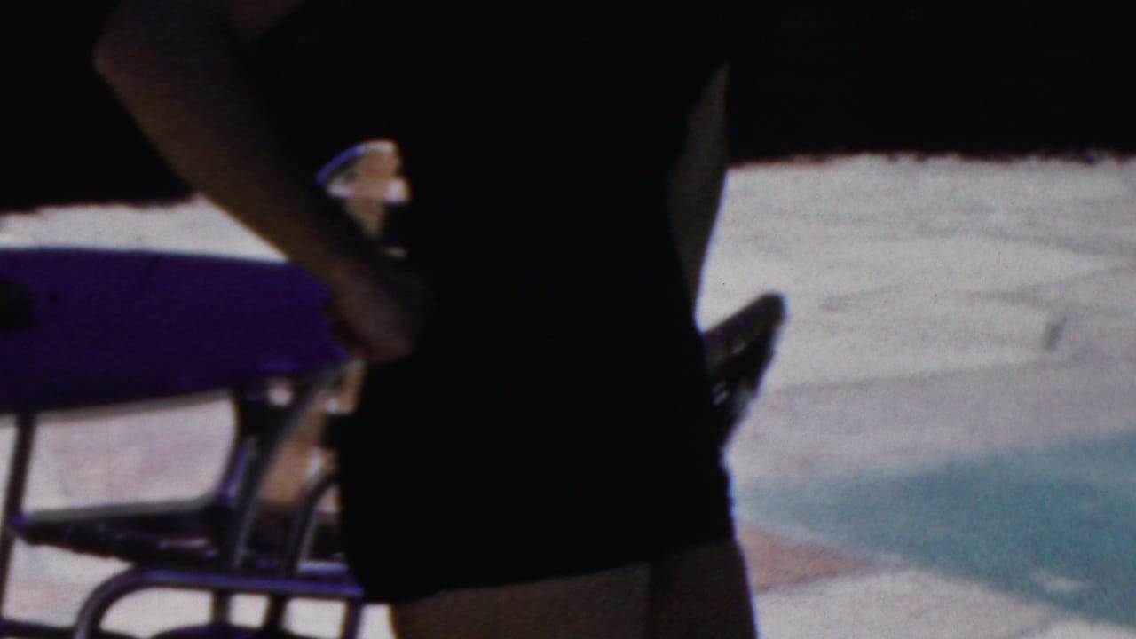 In 1949 Seaside, New Jersey home-movie footage, a woman in a dark strapless swimsuit is framed from torso to thighs near metal patio chairs and sunlit paving.