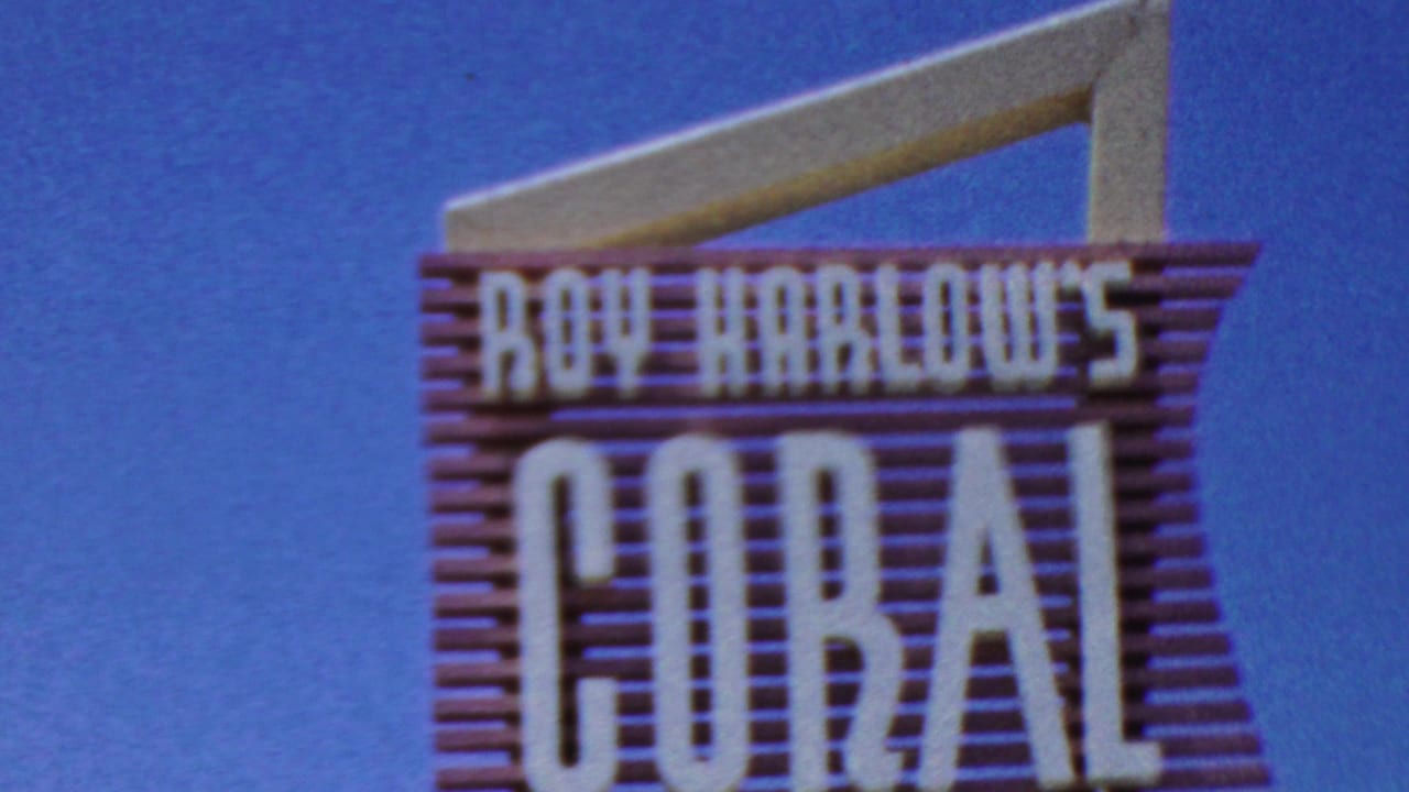 Large sign against blue sky reading "Roy Harlow's Coral."