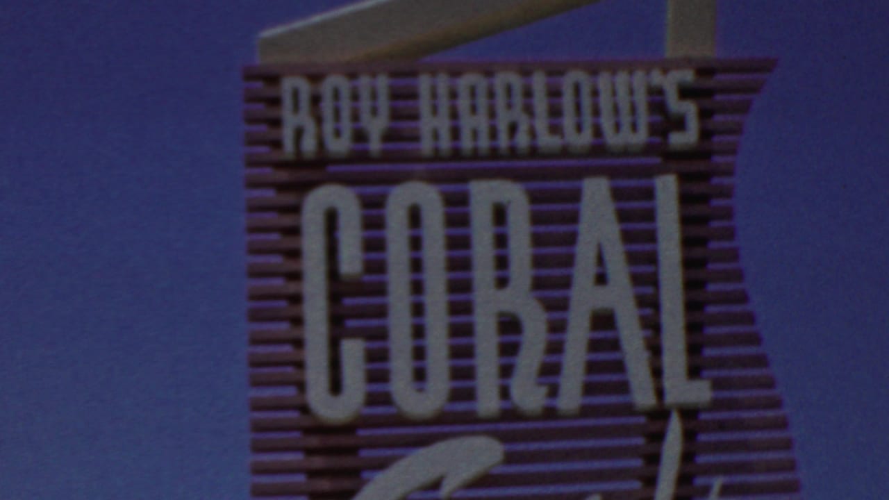 1949 8mm frame from Seaside, New Jersey showing the upper portion of the Roy Harlow's Coral Sands sign with block lettering and cursive script against a deep blue sky.