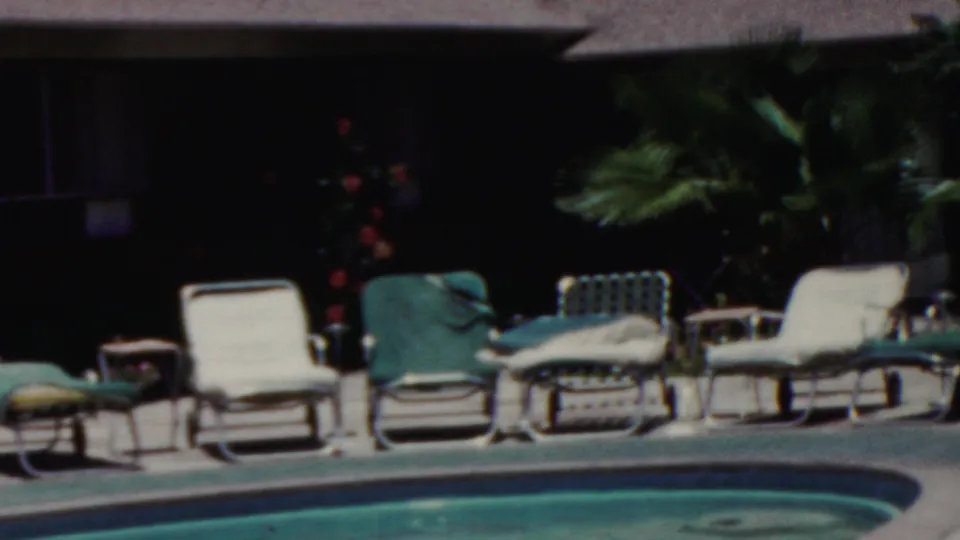 1949 Seaside, New Jersey poolside view with rows of lounge chairs, green cushions, a small table, and tropical-looking plants behind the deck.