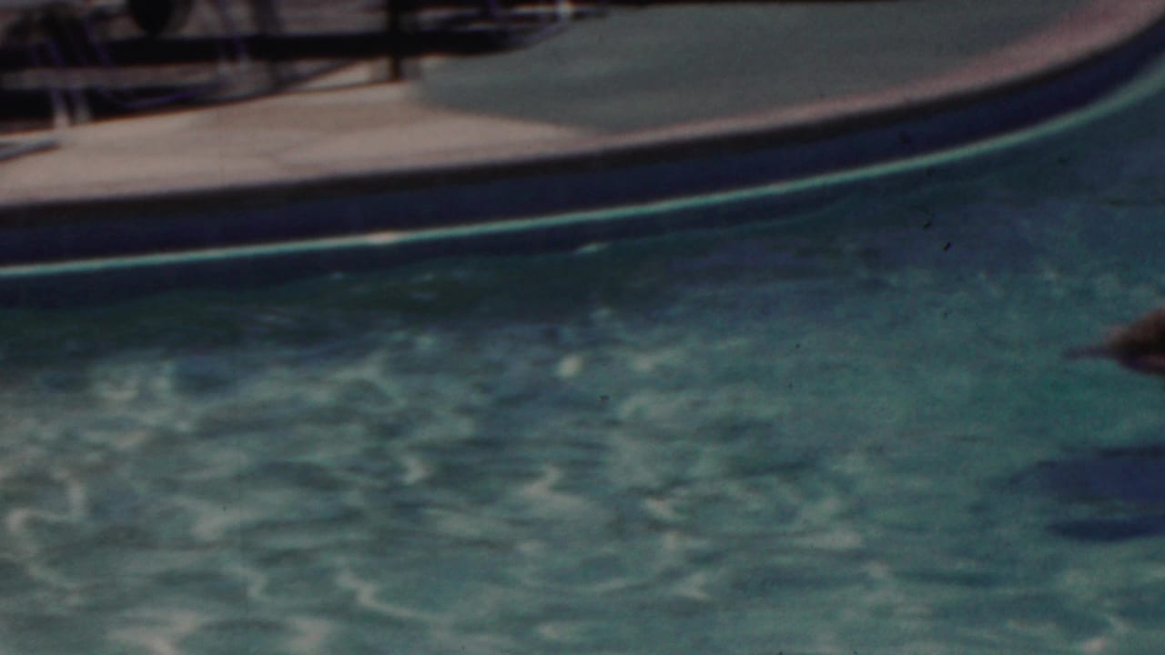 1949 Seaside, New Jersey 8mm frame showing turquoise pool water, curved coping, and indistinct poolside furniture in bright outdoor light.