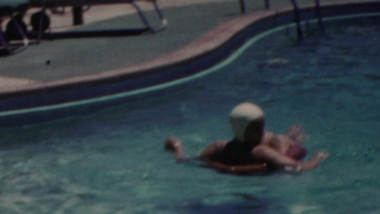 Woman in a white swim cap floats in a swimming pool on an inflatable ring.