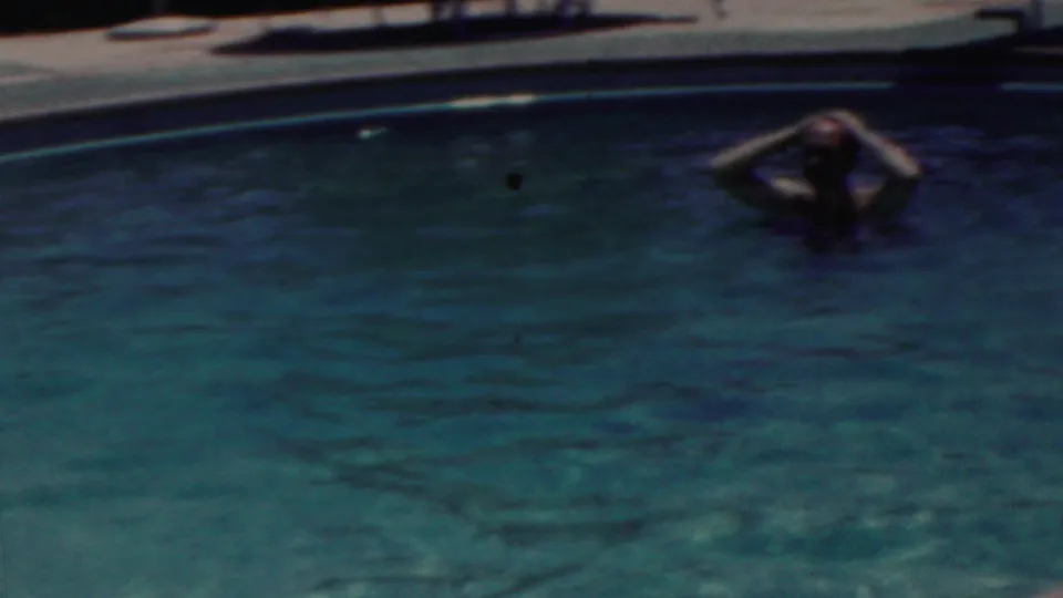 1949 Seaside, New Jersey home-movie frame showing a man in the pool near the far edge, with rippled water and pool coping behind him.