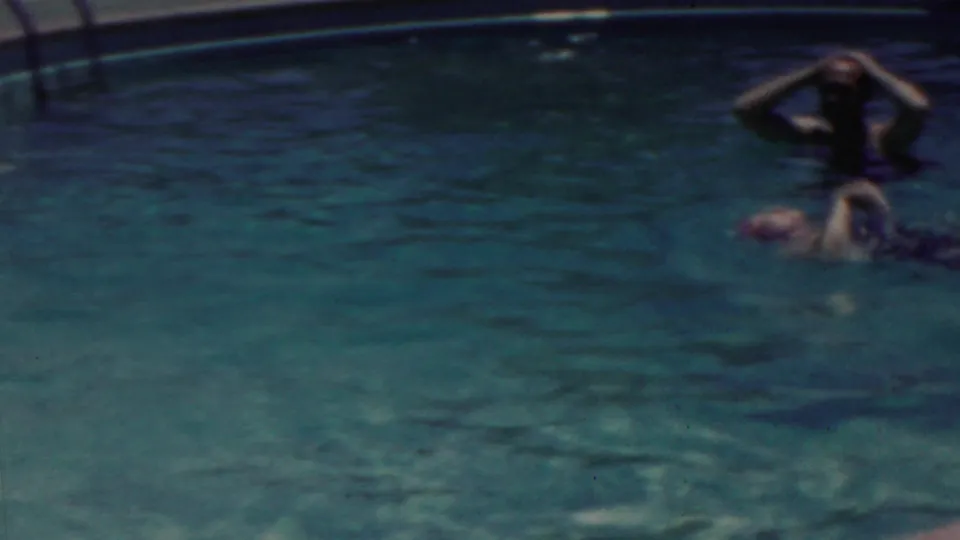 1949 Seaside, New Jersey home-movie frame with an adult swimmer upright near the far side of the pool and another person floating or swimming at right.