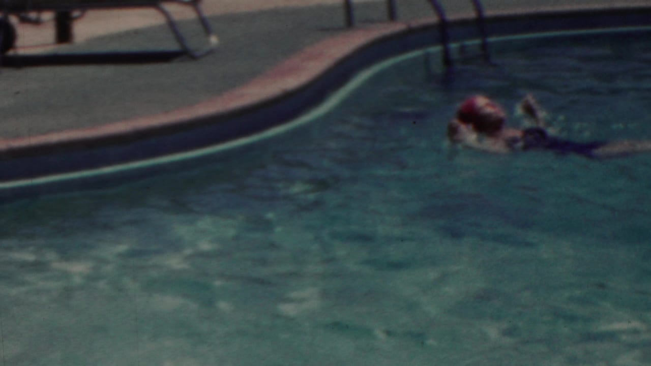 In 1949 Seaside, New Jersey home-movie footage, a woman wearing a bright pink swim cap swims across blue-green pool water near the curved pool edge.