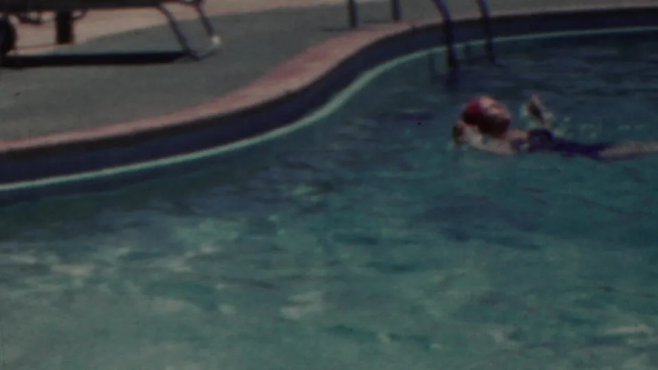 In 1949 Seaside, New Jersey home-movie footage, a woman wearing a bright pink swim cap swims across blue-green pool water near the curved pool edge.