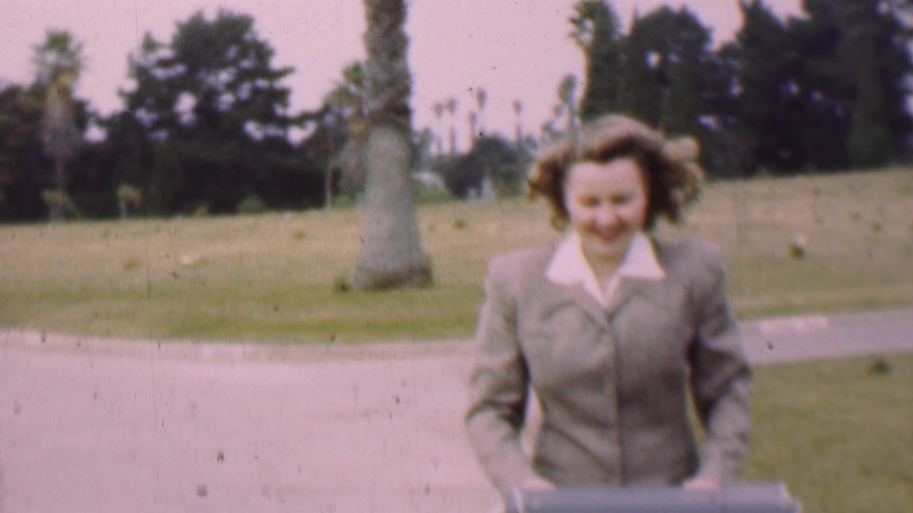 Smiling woman walks toward the camera on a park path.