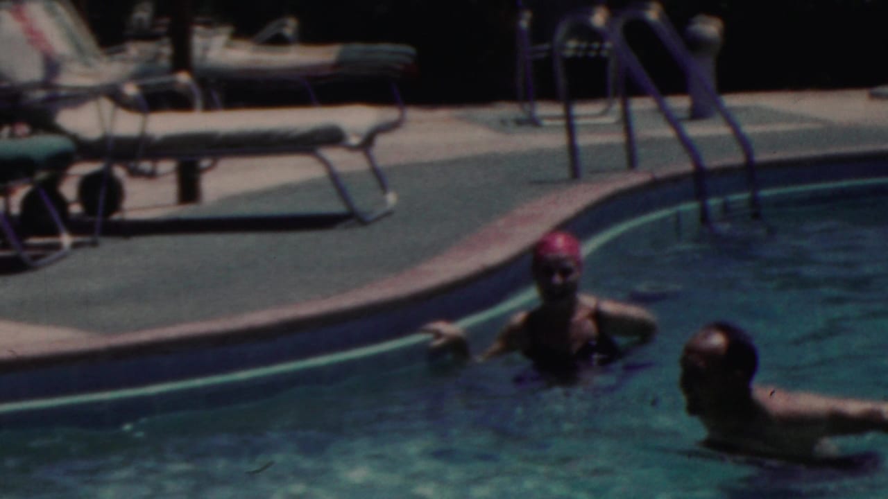 Two adults remain in the swimming pool in the 1949 Seaside, New Jersey footage, one in a red swim cap and the other turned toward the pool edge beneath strong sunlight.