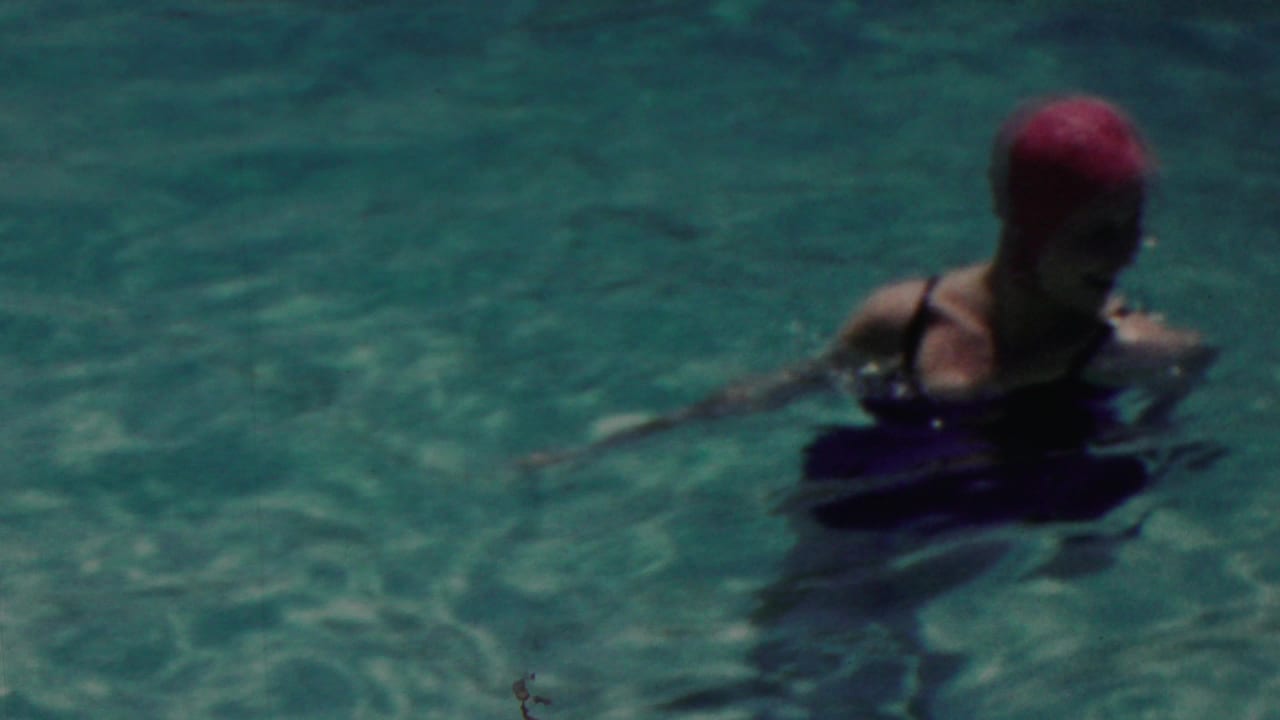In Seaside, New Jersey, 1949 home-movie footage, a woman in a red swim cap and dark swimsuit stands chest-deep in a sunlit pool.