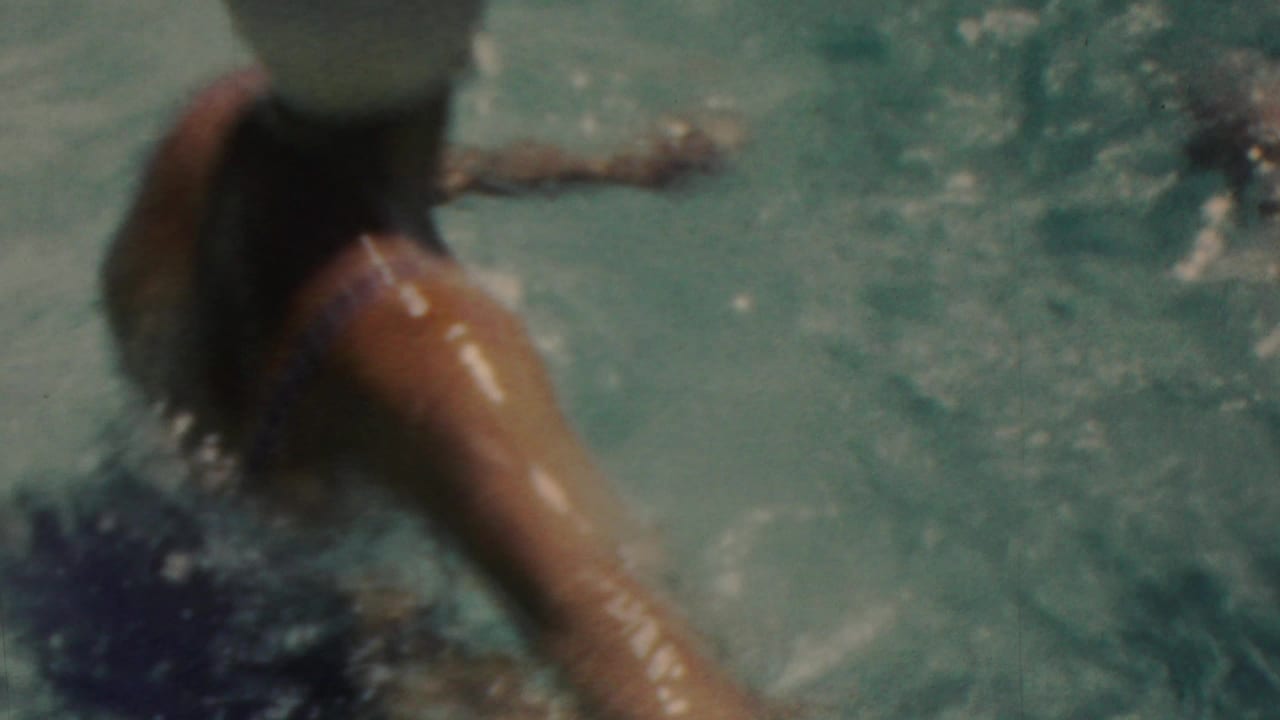 Close handheld view of the capped swimmer, partly submerged, with an arm extended through the water during the Seaside, New Jersey swimming scene.