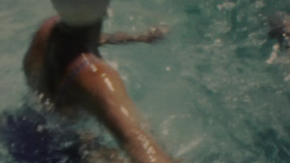 Close handheld view of the capped swimmer, partly submerged, with an arm extended through the water during the Seaside, New Jersey swimming scene.