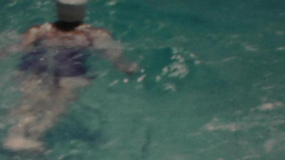 In this 1949 Seaside, New Jersey home-movie frame, a swimmer is partly submerged in rippling blue-green water with soft focus and visible film grain.