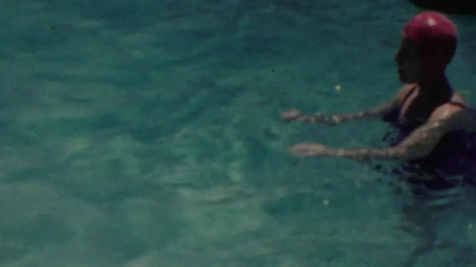 A woman wearing a red swim cap and dark swimsuit appears to wade in blue-green water in the supplied 1949 Seaside, New Jersey footage.