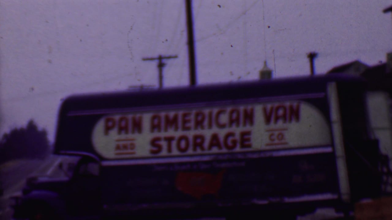 1956 Phoenix street view of a dark Pan American Van and Storage Co. truck with red lettering on a white side sign, overhead wires, and soft 8mm color shift.