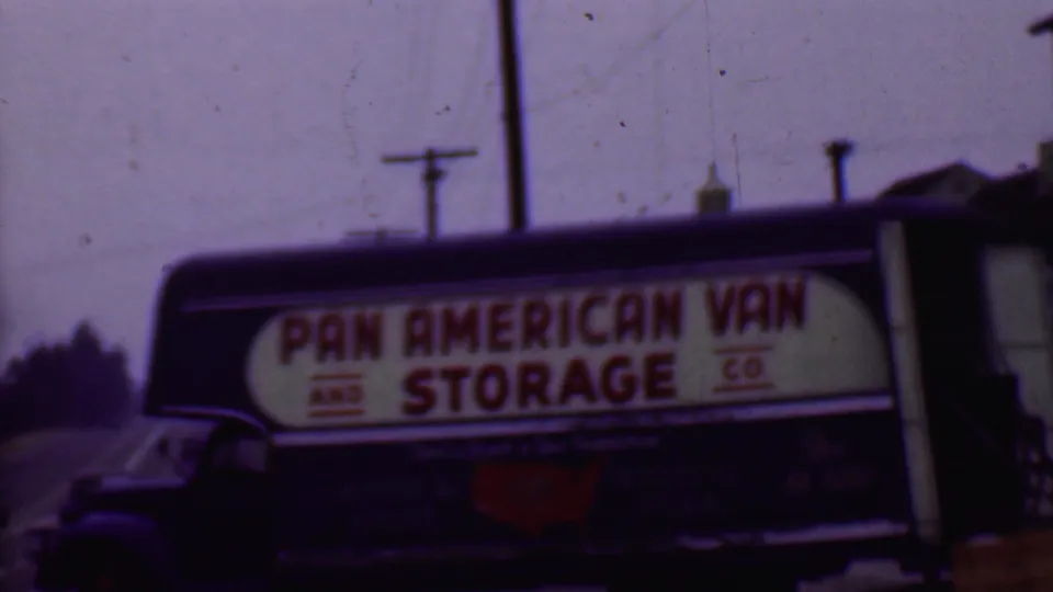 1956 Phoenix street view of a dark Pan American Van and Storage Co. truck with red lettering on a white side sign, overhead wires, and soft 8mm color shift.