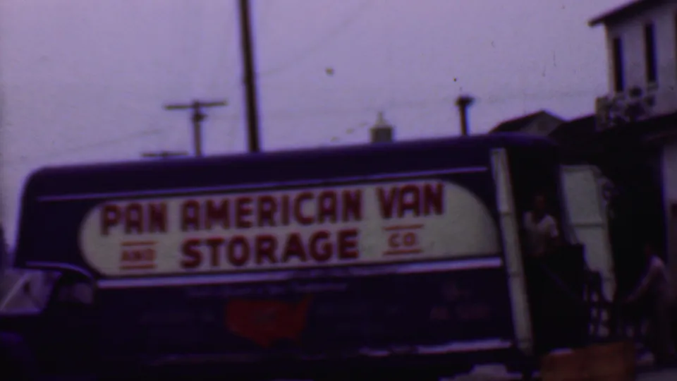 Final 1956 Phoenix view of the branded storage truck, with the bold red sign text, red U.S. map graphic, utility poles, and a person partly visible at the rear doorway.
