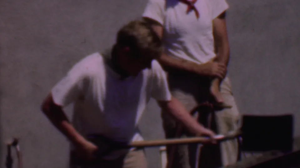 In the final frame, one man mixes cement in the wheelbarrow with a shovel while another stands behind him with a hose in bright 1956 Phoenix sunlight.