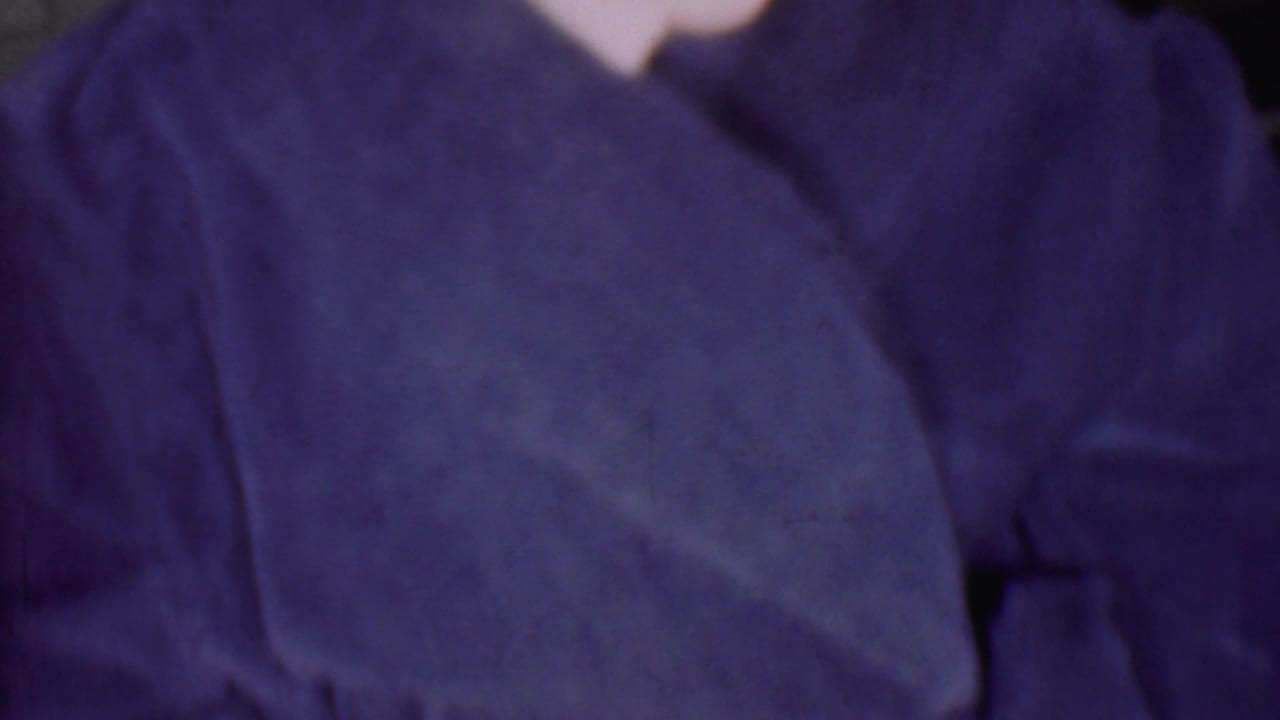 Dark blue robe fills most of the frame, with a small hand and blurred shoulder area visible.