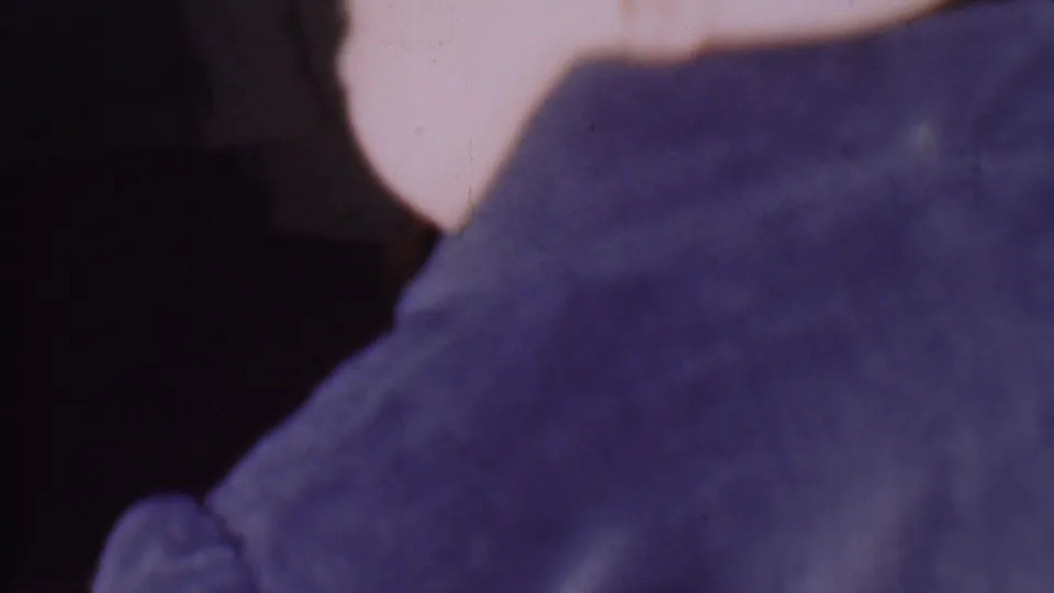 Cropped side-back view from the 1956 Phoenix home movie, showing the child turned in a dark blue bathrobe with the face mostly outside the frame.