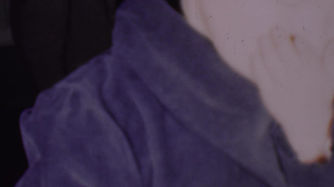 Partial profile of a woman in a blue-purple head covering.