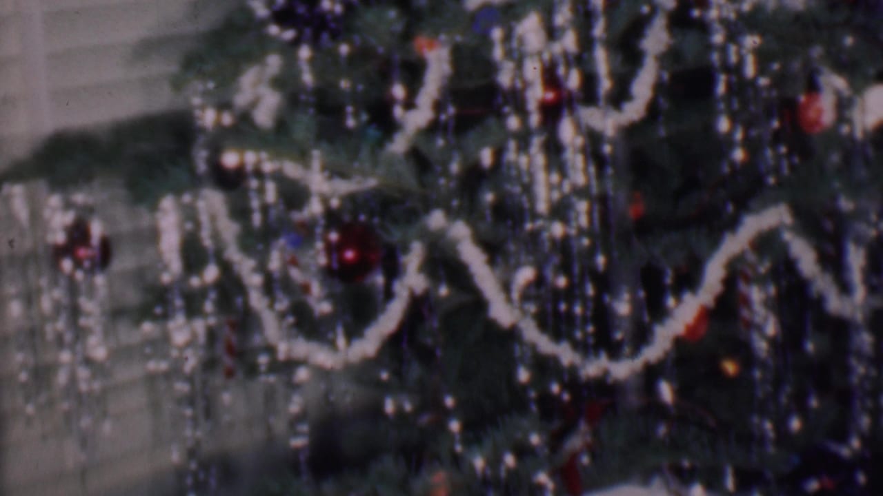 Close 1956 Phoenix home-movie frame of Christmas tree decorations, including white garland loops, red and dark ornaments, and dense reflective tinsel-like strands.