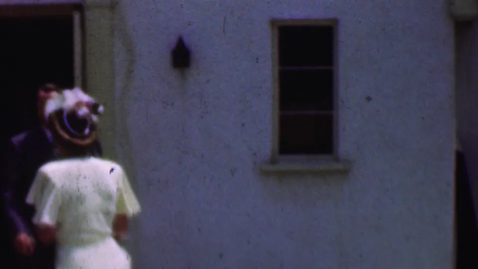 In the Dallas church entrance scene, the woman in a white dress and hat stands near a man in a dark suit as they move around the open doorway.