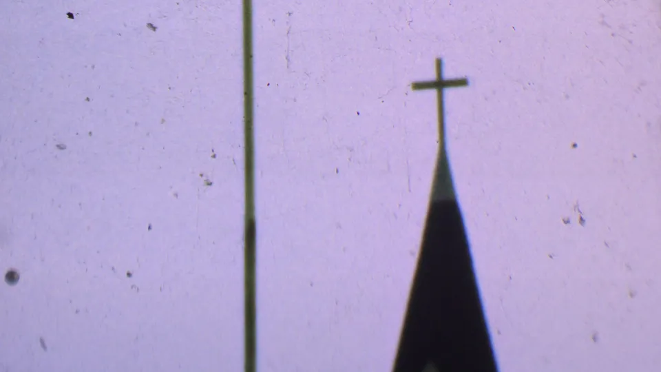 1956 Dallas frame with a close, soft-focus view of the church steeple top and cross, with a vertical film or scan line and dust visible against the sky.