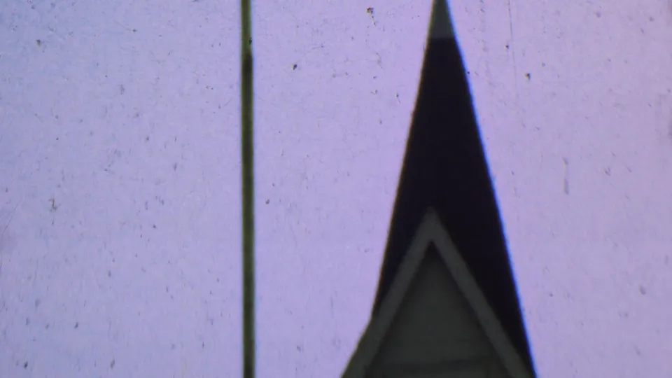 Dallas, Texas 1956 8mm frame with the dark upper church steeple, faint gable trim, a vertical pole, and visible film wear in the sky.