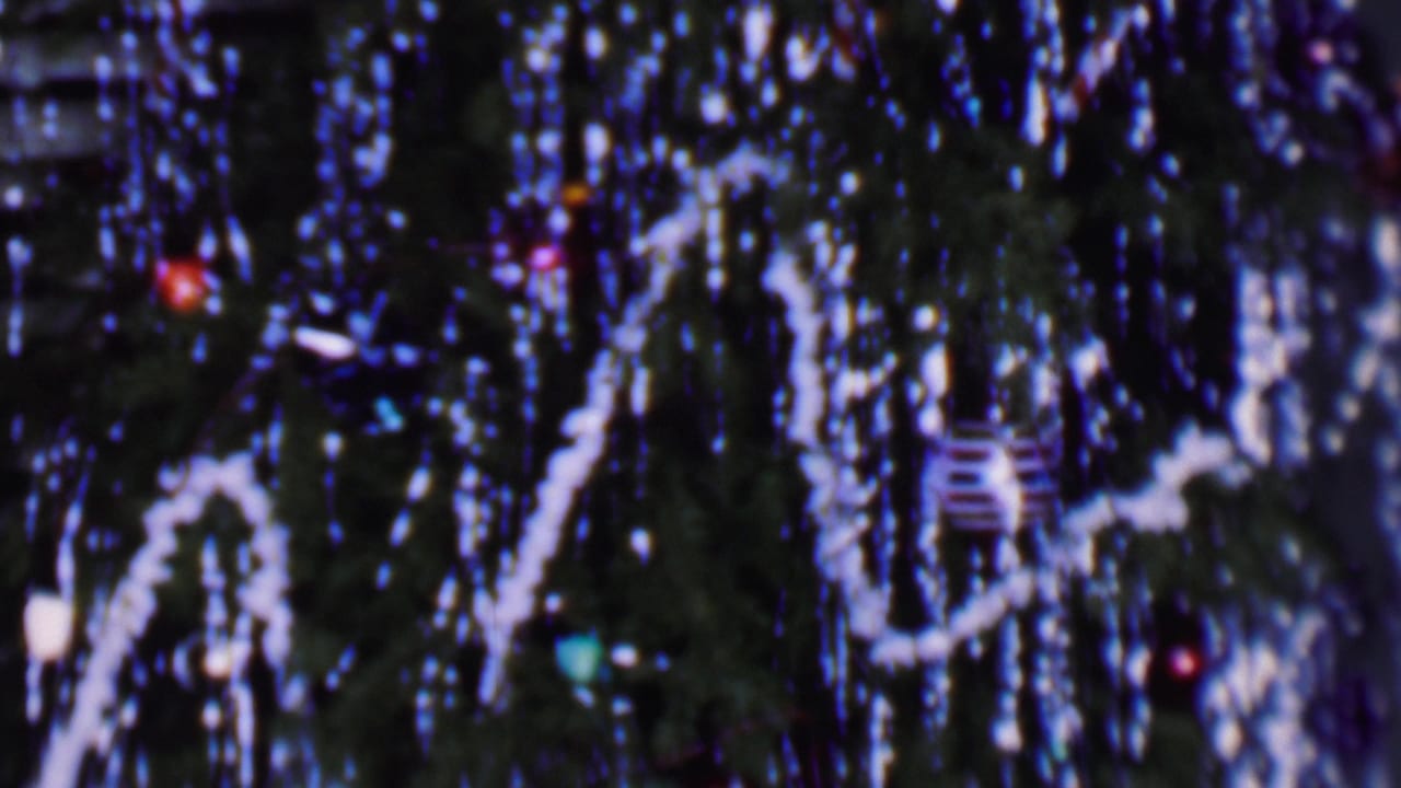 Phoenix, Arizona 1956 home-movie frame showing a close, soft-focus view of a Christmas tree with silver tinsel, white garland, and small colored ornaments.