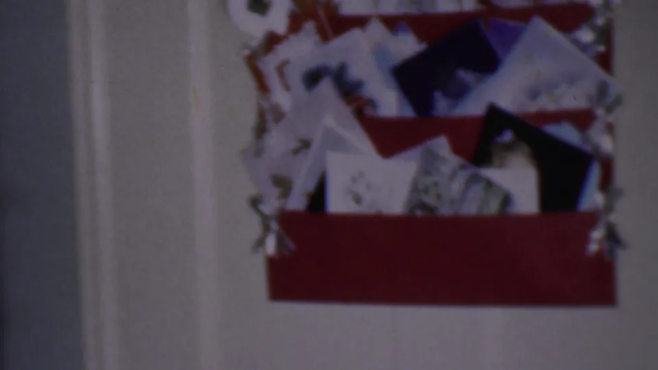 Soft 8mm frame of a crowded Christmas card and letter display on a white interior door, with red trim and overlapping cards visible.