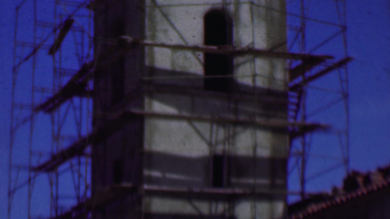 Tall scaffolded tower with open windows and exterior stair platforms.