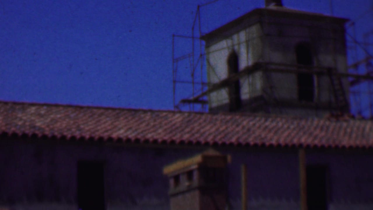 Close view of a red tile roof with two tower structures and scaffolding.