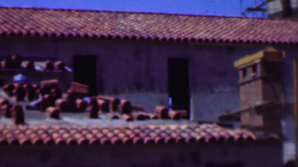 1956 Dallas construction frame with terracotta roofing materials laid across a sloped red tile roof near unfinished door and window openings.