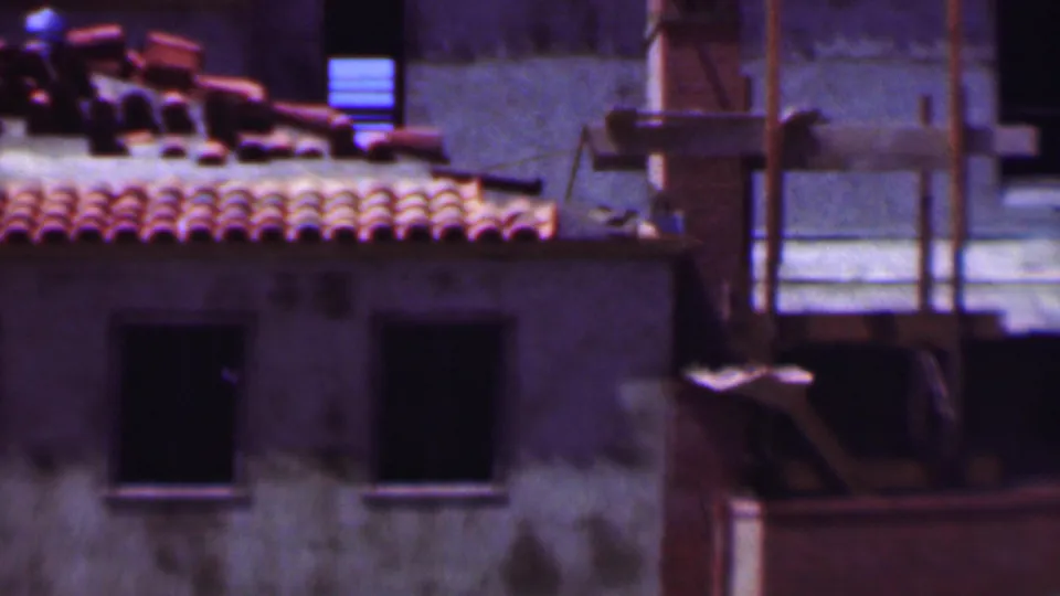 1956 Dallas 8mm frame showing an older building with red roof tiles, dark windows, and scaffolding or support poles along the exterior.
