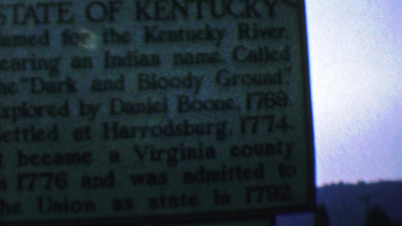 Kentucky historical marker with readable text and sky behind it.