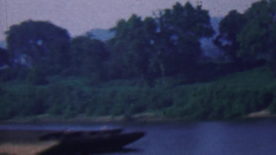 1961 metadata-identified Kentucky river scene with a dark barge crossing the foreground below dense trees and a sloped green bank.