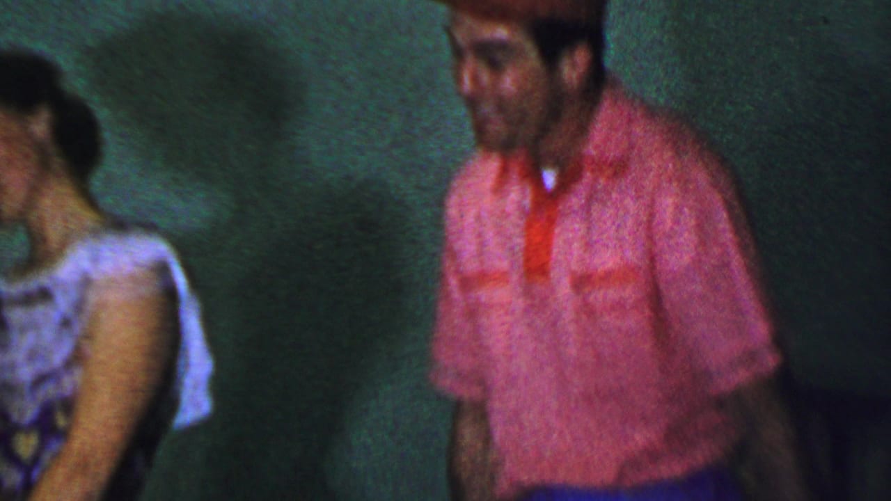 Woman in a light dress sits or leans near a man in a red shirt and cap.