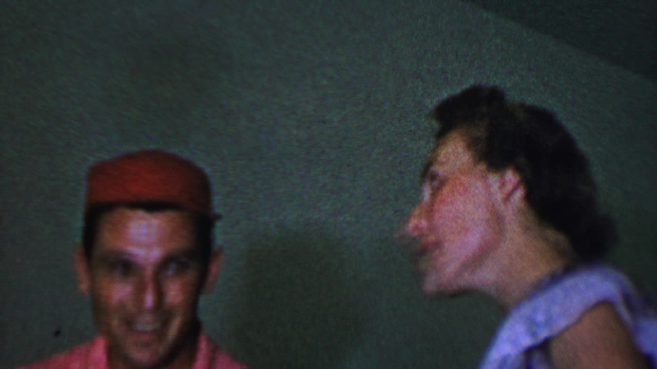 Man in a red cap faces the camera while a woman appears in profile at right.